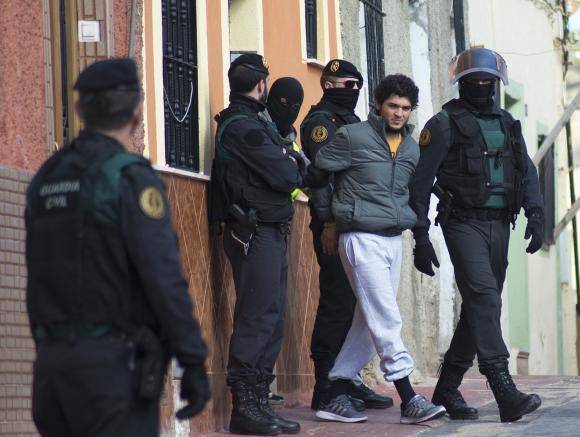Spanish civil guards lead a detained man suspected of using social media to recruit people to violent groups like the Islamic State, in Spain's North African enclave Melilla