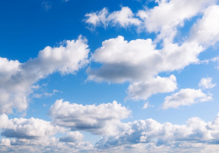 Bright, fluffy cumulus clouds in front of a clear blue sky.
